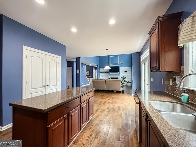 35 Paddle Boat Cv, Senoia, GA 30276 - kitchen featuring light wood finished floors, backsplash, dishwasher, dark stone counters, and decorative light fixtures