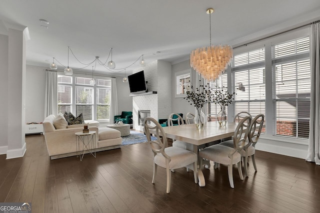 545 Hanlon Way, Alpharetta, GA 30009 - dining area featuring a glass covered fireplace, plenty of natural light, a chandelier, and dark wood-type flooring