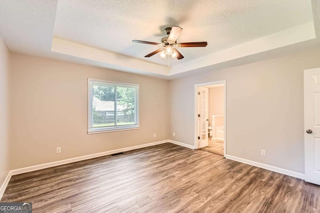 11473 Summer Creek Dr, Hampton, GA 30228 - unfurnished bedroom featuring a tray ceiling, wood finished floors, a textured ceiling, ensuite bathroom, and ceiling fan