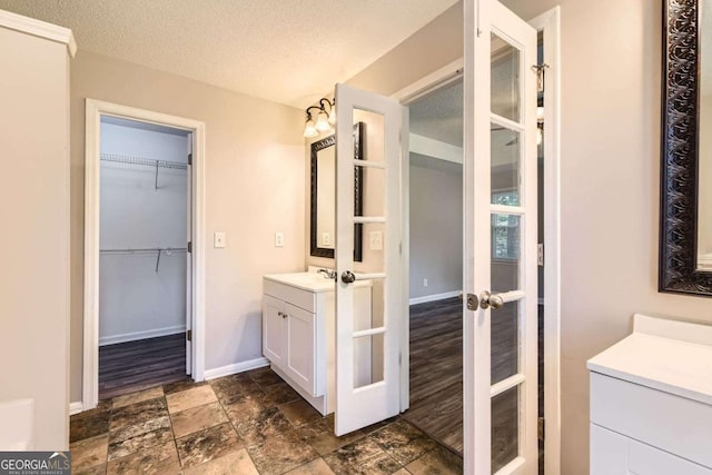 11473 Summer Creek Dr, Hampton, GA 30228 - full bathroom featuring vanity, french doors, stone finish flooring, a spacious closet, and a textured ceiling