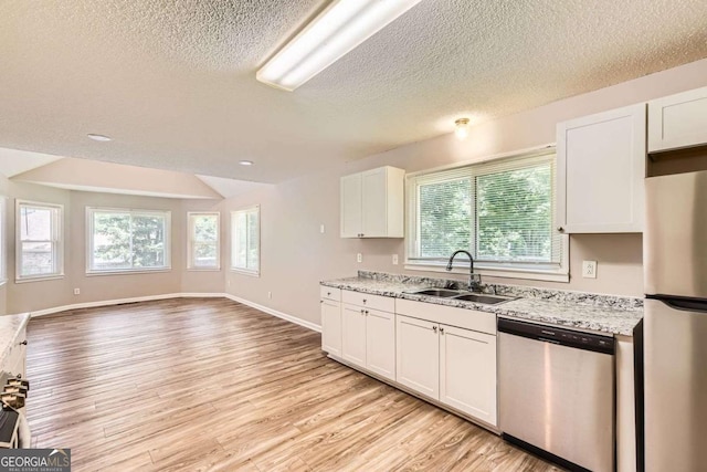11473 Summer Creek Dr, Hampton, GA 30228 - kitchen featuring stainless steel appliances, light wood-type flooring, plenty of natural light, a textured ceiling, and light stone countertops