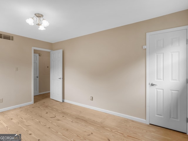 778 Leguin Mill Rd, Locust Grove, GA 30248 - unfurnished bedroom with light wood finished floors and a chandelier