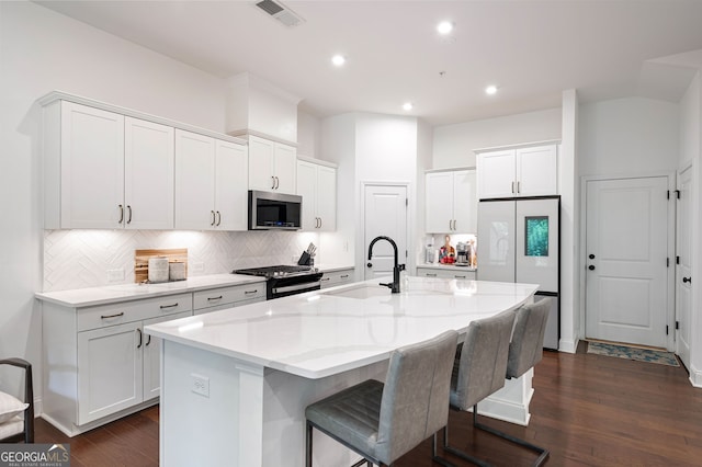 203 Holden Way, Woodstock, GA 30189 - kitchen featuring stainless steel appliances, a center island with sink, decorative backsplash, white cabinets, and dark wood-style flooring