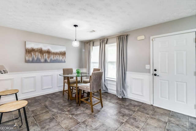 1147 Dunivin Dr, Jonesboro, GA 30238 - dining room featuring a wainscoted wall, a decorative wall, and a textured ceiling
