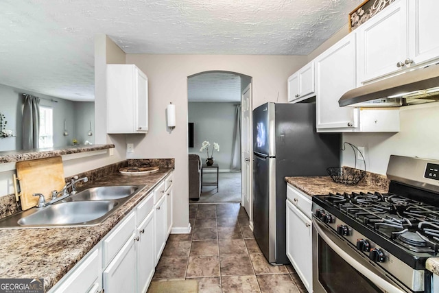 1147 Dunivin Dr, Jonesboro, GA 30238 - kitchen with appliances with stainless steel finishes, under cabinet range hood, arched walkways, white cabinetry, and a textured ceiling