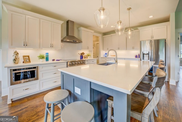 3076 E Lake Rd, Mcdonough, GA 30252 - kitchen featuring wall chimney exhaust hood, stainless steel appliances, white cabinets, a breakfast bar, and an island with sink