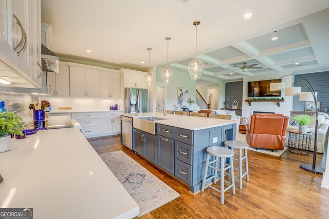 3076 E Lake Rd, Mcdonough, GA 30252 - kitchen featuring appliances with stainless steel finishes, coffered ceiling, white cabinetry, a ceiling fan, and a kitchen bar