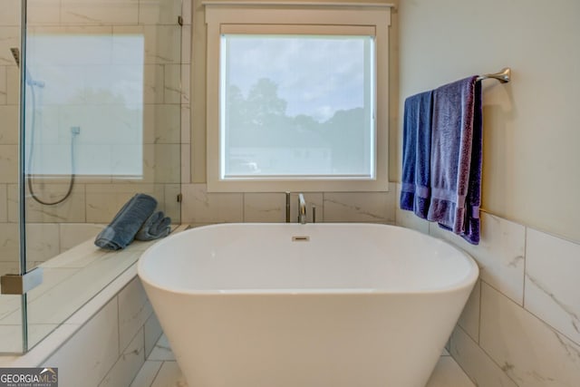 3076 E Lake Rd, Mcdonough, GA 30252 - bathroom featuring healthy amount of natural light, a freestanding tub, and tile walls