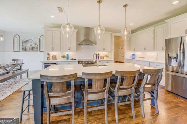 3076 E Lake Rd, Mcdonough, GA 30252 - kitchen featuring stainless steel refrigerator with ice dispenser, wall chimney exhaust hood, a kitchen island with sink, light countertops, and white cabinets