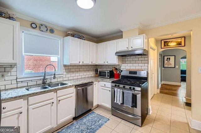 1134 Jefferson Ave, East Point, GA 30344 - kitchen featuring stainless steel appliances, under cabinet range hood, white cabinets, backsplash, and ornamental molding
