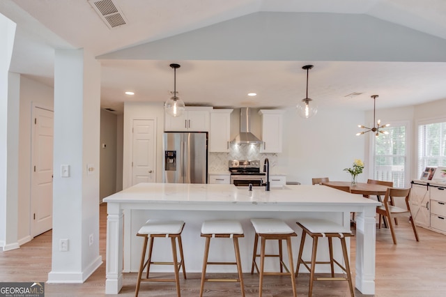 1406 Marshview Ct, Hoschton, GA 30548 - kitchen featuring stainless steel appliances, decorative backsplash, wall chimney exhaust hood, a kitchen breakfast bar, and white cabinets