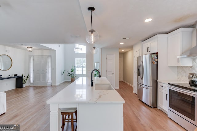 1406 Marshview Ct, Hoschton, GA 30548 - kitchen featuring stainless steel appliances, open floor plan, light wood-style floors, white cabinetry, and recessed lighting