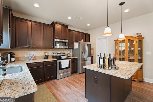 1001 Hartwell Rd, Locust Grove, GA 30248 - kitchen featuring stainless steel appliances, a kitchen island, dark brown cabinets, light wood-style flooring, and tasteful backsplash