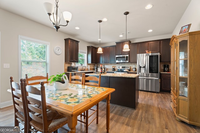 1001 Hartwell Rd, Locust Grove, GA 30248 - kitchen with appliances with stainless steel finishes, dark brown cabinetry, tasteful backsplash, wood finished floors, and light stone counters