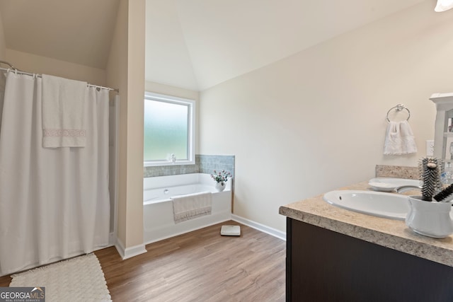 1001 Hartwell Rd, Locust Grove, GA 30248 - full bathroom featuring wood finished floors, a bath, double vanity, vaulted ceiling, and a shower with shower curtain