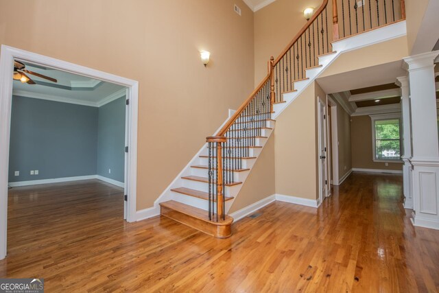 303 Sage Meadows Ln, Bonaire, GA 31005 - stairs featuring decorative columns, ornamental molding, wood finished floors, ceiling fan, and a high ceiling