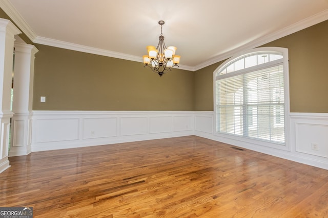 303 Sage Meadows Ln, Bonaire, GA 31005 - unfurnished room with a chandelier, wood finished floors, crown molding, wainscoting, and ornate columns