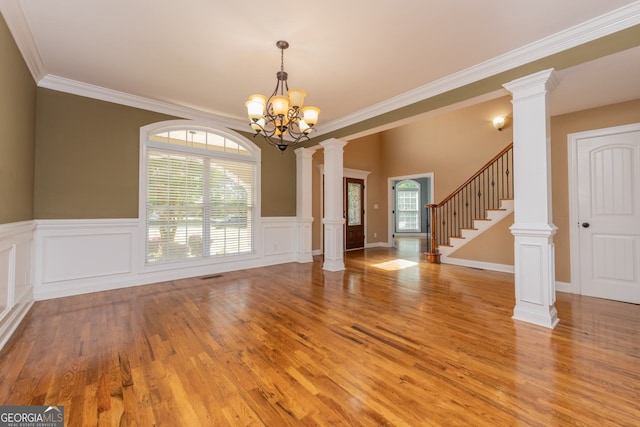 303 Sage Meadows Ln, Bonaire, GA 31005 - empty room with ornate columns, a chandelier, light wood-type flooring, ornamental molding, and a wainscoted wall