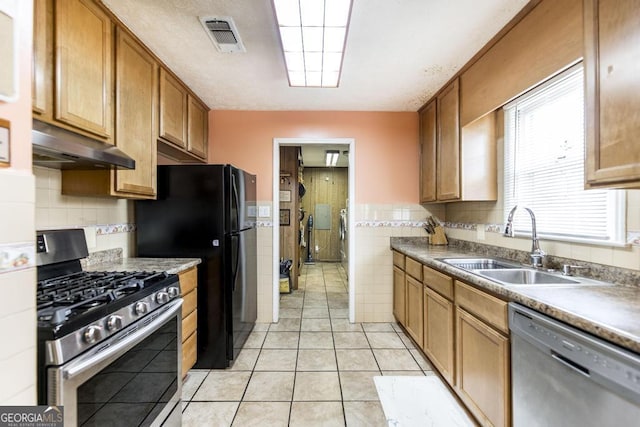 4782 Two Oak Dr, Macon, GA 31210 - kitchen featuring stainless steel appliances, under cabinet range hood, tile walls, light tile patterned floors, and brown cabinets
