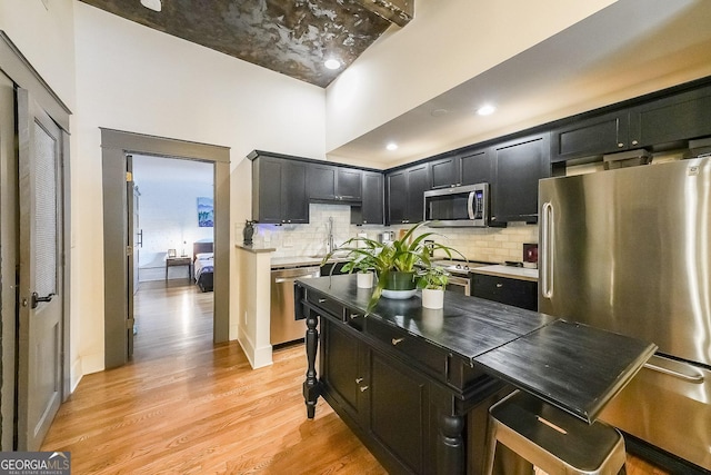 1026 Saint Charles Ave NE Unit 15, Atlanta, GA 30306 - kitchen with stainless steel appliances, dark cabinets, decorative backsplash, and light wood finished floors
