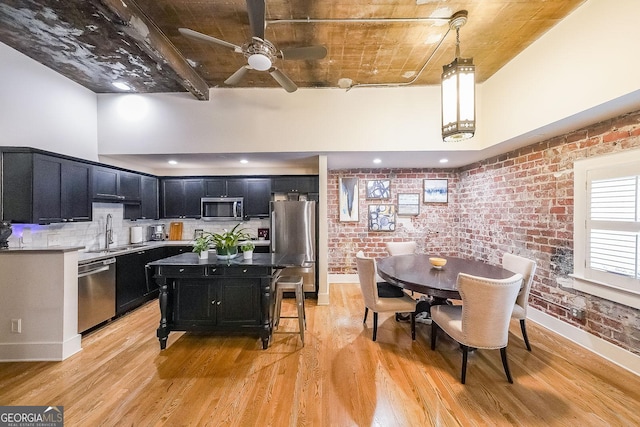 1026 Saint Charles Ave NE Unit 15, Atlanta, GA 30306 - kitchen with appliances with stainless steel finishes, dark cabinetry, brick wall, light wood-style floors, and a ceiling fan