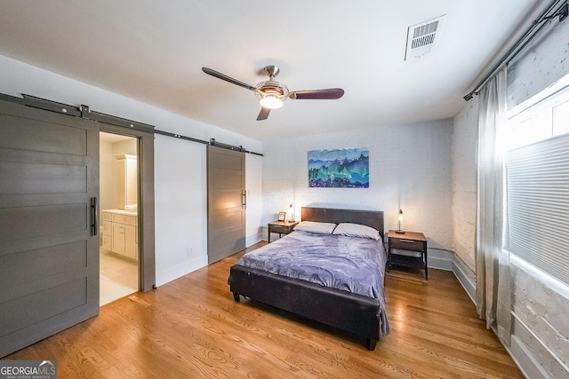 1026 Saint Charles Ave NE Unit 15, Atlanta, GA 30306 - bedroom with a barn door, light wood-type flooring, ceiling fan, and connected bathroom