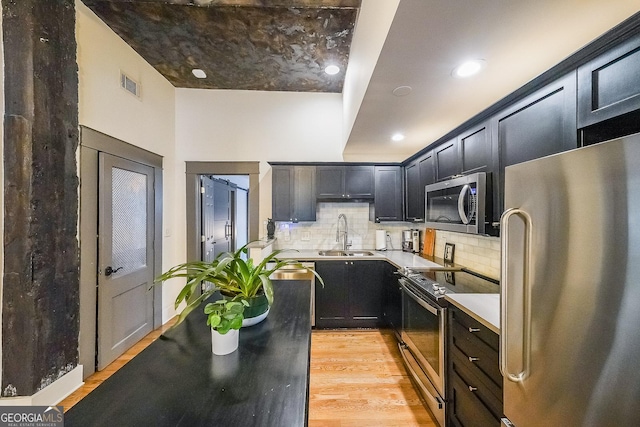 1026 Saint Charles Ave NE Unit 15, Atlanta, GA 30306 - kitchen featuring appliances with stainless steel finishes, decorative backsplash, light wood-type flooring, light countertops, and dark cabinetry