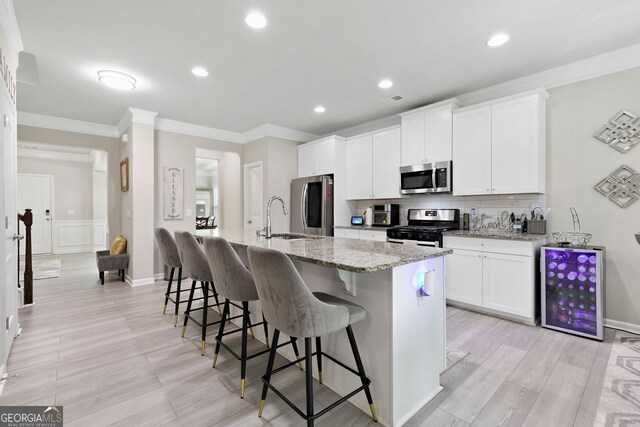 140 Canyons Ct, Hampton, GA 30228 - kitchen featuring appliances with stainless steel finishes, a kitchen breakfast bar, a center island with sink, ornamental molding, and tasteful backsplash