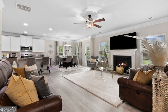 140 Canyons Ct, Hampton, GA 30228 - living area with light wood-style floors, ornamental molding, a ceiling fan, recessed lighting, and a warm lit fireplace