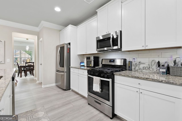 140 Canyons Ct, Hampton, GA 30228 - kitchen featuring appliances with stainless steel finishes, ornamental molding, white cabinetry, backsplash, and light stone countertops