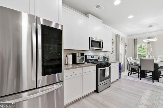 140 Canyons Ct, Hampton, GA 30228 - kitchen featuring appliances with stainless steel finishes, white cabinetry, light stone counters, light wood-style flooring, and recessed lighting
