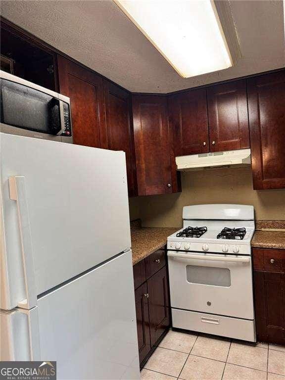 1807 Ashborough Cir SE Unit B, Marietta, GA 30067 - kitchen featuring white appliances, under cabinet range hood, light tile patterned floors, and dark brown cabinetry