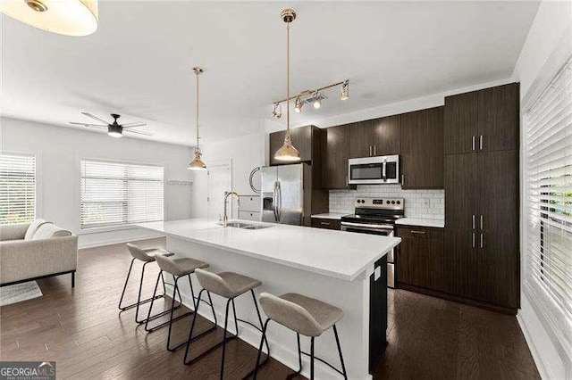 19 Moda Ln, Atlanta, GA 30316 - kitchen with appliances with stainless steel finishes, a breakfast bar area, decorative backsplash, ceiling fan, and dark brown cabinets