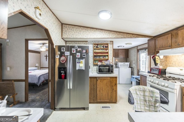 912 Druid St, Dublin, GA 31021 - kitchen with wallpapered walls, stainless steel fridge, white gas stove, washer / dryer, and black microwave