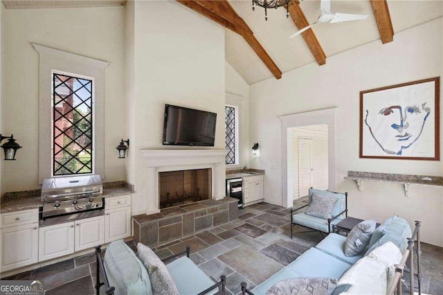 2883 Andrews Dr NW, Atlanta, GA 30305 - living area featuring wine cooler, beam ceiling, stone tile floors, a fireplace with raised hearth, and high vaulted ceiling