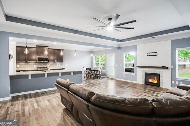 132 Berkleigh Trails Dr, Hiram, GA 30141 - living area with wood finished floors, a ceiling fan, a tile fireplace, and a tray ceiling
