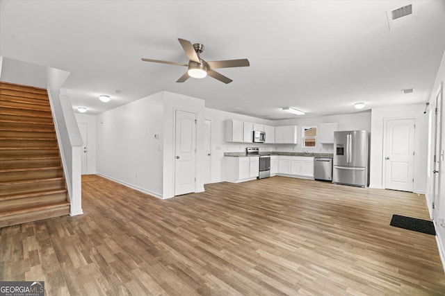 104 Middleton Ct, Chatsworth, GA 30705 - unfurnished living room with a ceiling fan, stairs, and light wood-style floors