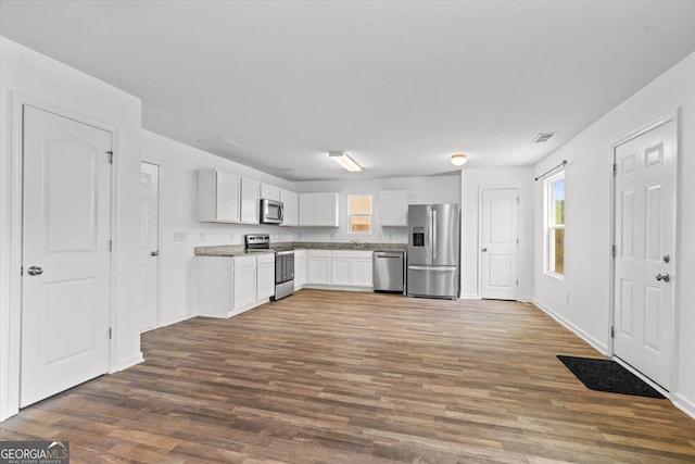 104 Middleton Ct, Chatsworth, GA 30705 - kitchen featuring appliances with stainless steel finishes, dark wood-style flooring, plenty of natural light, and white cabinetry