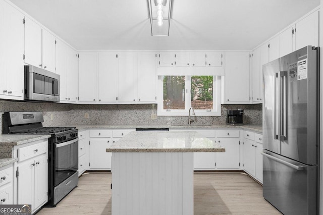 2945 Thompson Mill Rd, Gainesville, GA 30506 - kitchen featuring appliances with stainless steel finishes, light wood-type flooring, decorative backsplash, and white cabinets