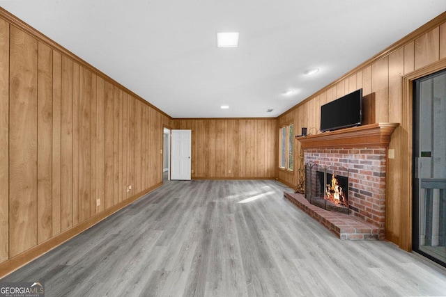 2945 Thompson Mill Rd, Gainesville, GA 30506 - unfurnished living room with a fireplace, crown molding, wood walls, and light wood-style floors