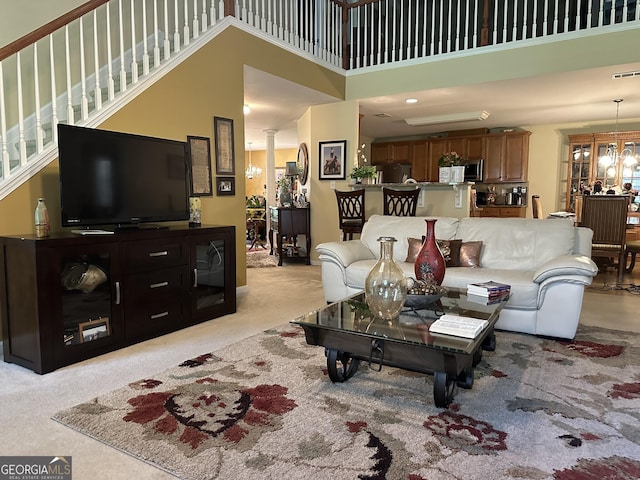 7946 Gossamer Dr, Fairburn, GA 30213 - living area with a high ceiling, light carpet, decorative columns, a chandelier, and stairway