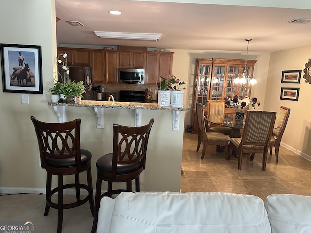 7946 Gossamer Dr, Fairburn, GA 30213 - kitchen with stainless steel microwave, range, freestanding refrigerator, a breakfast bar, and a peninsula