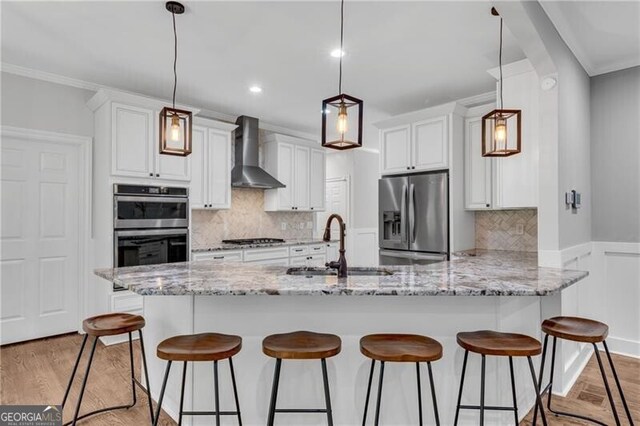 5301 Regency Lake Ct, Sugar Hill, GA 30518 - kitchen with wall chimney exhaust hood, appliances with stainless steel finishes, a peninsula, a breakfast bar area, and ornamental molding