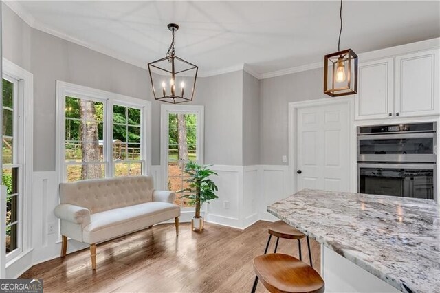 5301 Regency Lake Ct, Sugar Hill, GA 30518 - kitchen featuring stainless steel double oven, light stone counters, crown molding, wood finished floors, and white cabinetry