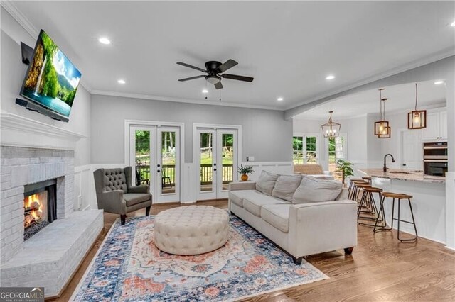 5301 Regency Lake Ct, Sugar Hill, GA 30518 - living room with light wood-style flooring, a ceiling fan, recessed lighting, crown molding, and a fireplace