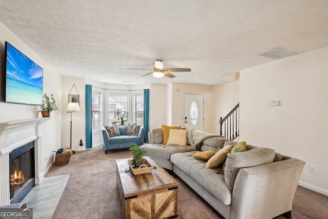 5686 Grindstone Dr, Buford, GA 30518 - living room featuring carpet flooring, a fireplace with flush hearth, a ceiling fan, stairs, and a textured ceiling