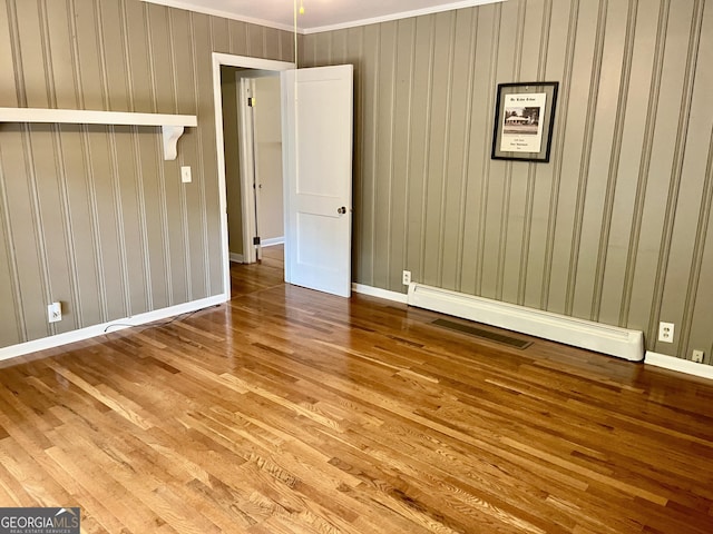 201 Glen Iris Dr, Monroe, GA 30655 - spare room featuring wood-type flooring, a baseboard heating unit, and crown molding