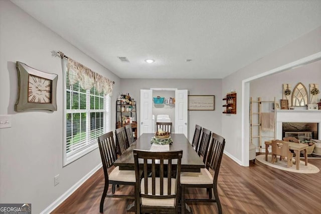 1050 Birdseye Vw, Locust Grove, GA 30248 - dining area with dark wood-type flooring, a textured ceiling, and a high end fireplace