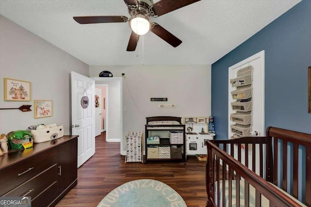 1050 Birdseye Vw, Locust Grove, GA 30248 - bedroom featuring dark wood-style floors, a nursery area, ceiling fan, and a textured ceiling
