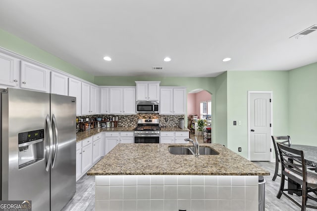 226 Creek View Ln, Acworth, GA 30102 - kitchen featuring stainless steel appliances, arched walkways, white cabinets, a kitchen island with sink, and recessed lighting